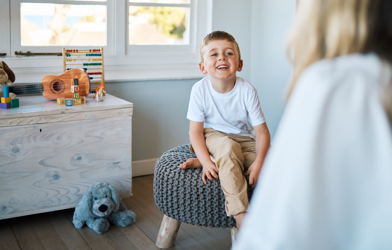 Happy young boy smiling during a therapy session in a playful room